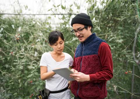 Two people looking at tablet in greenhouse