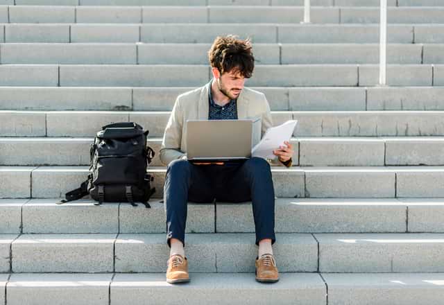 Man working on laptop outside on stairs