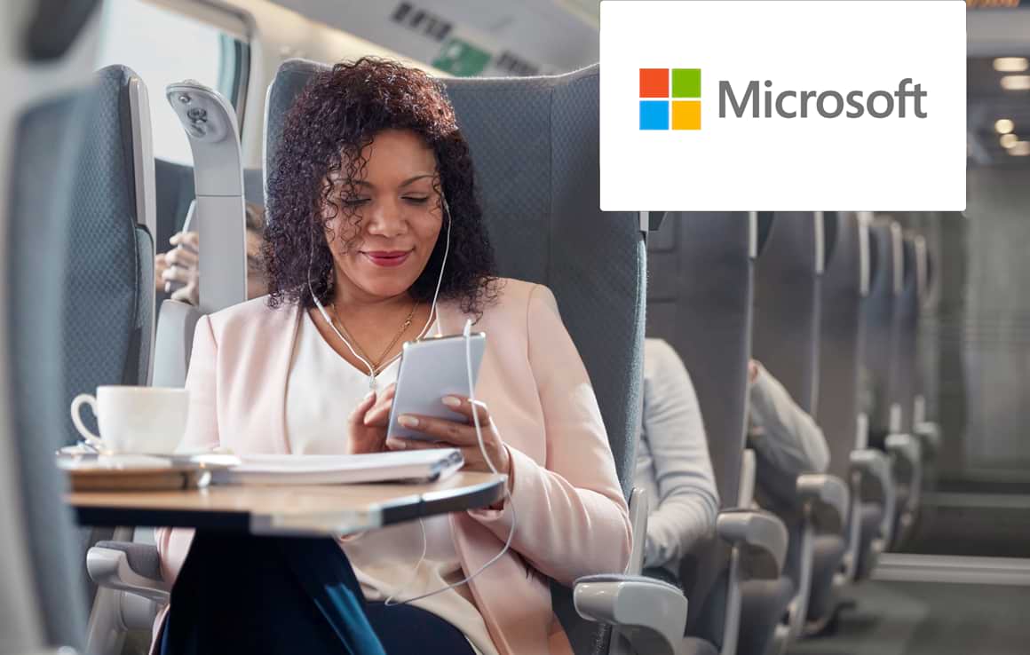 Woman working on phone while travelling on train with Microsoft logo in corner
