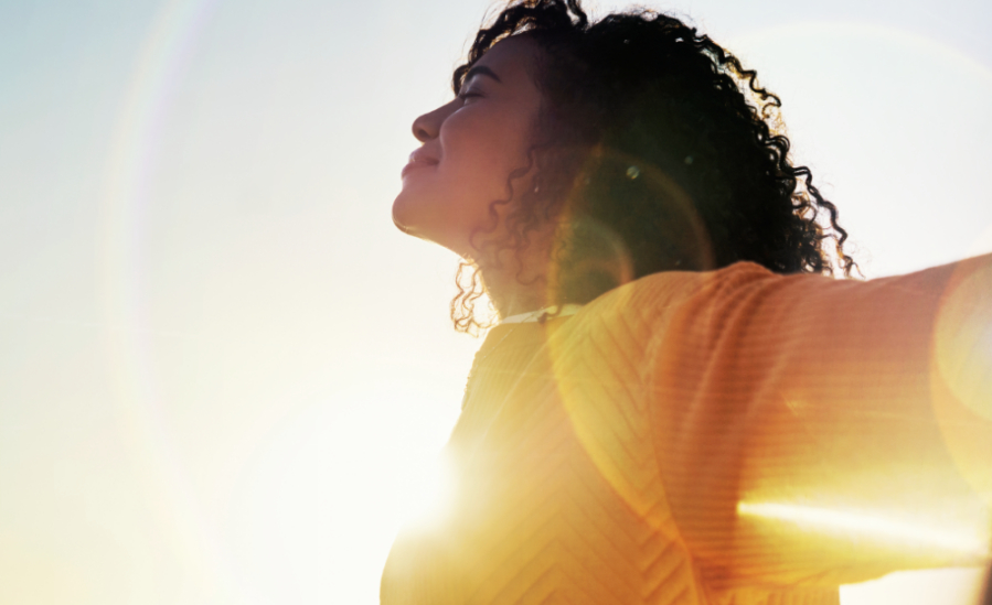 Girl with outstretched arms in the sunshine.