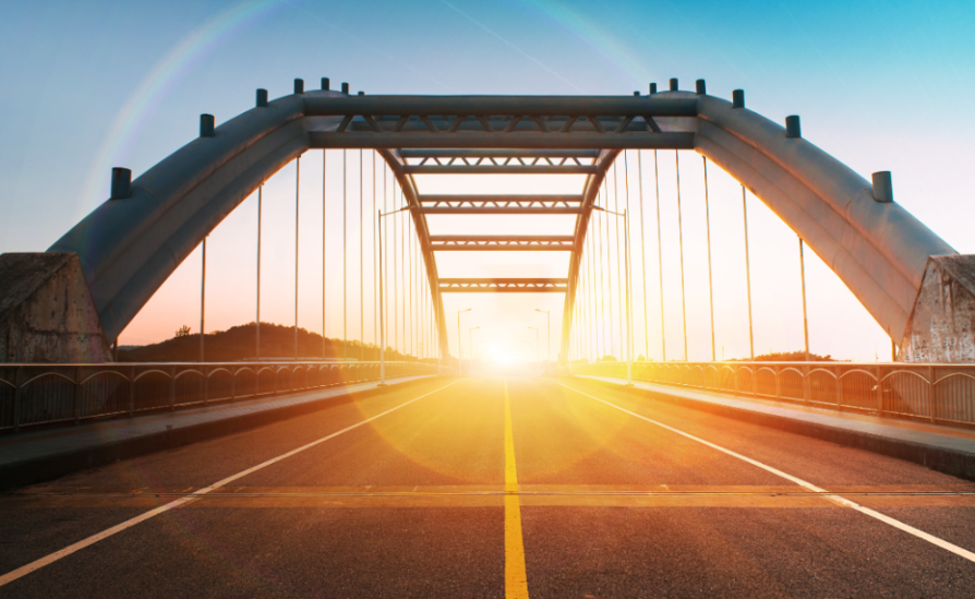 Sun setting on the horizon, through a bridge.