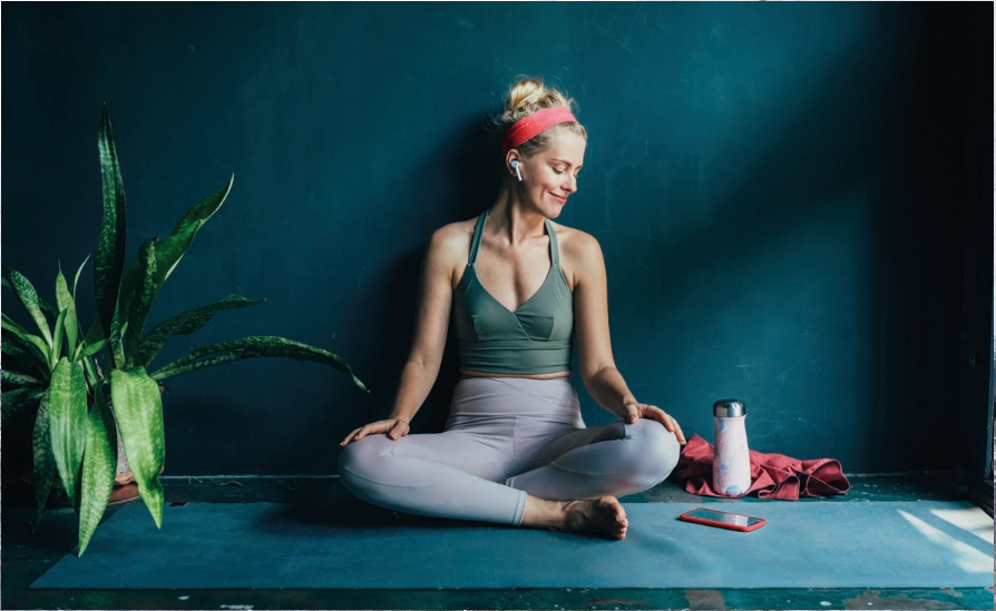 A woman sitting cross legged on a yoga mat.