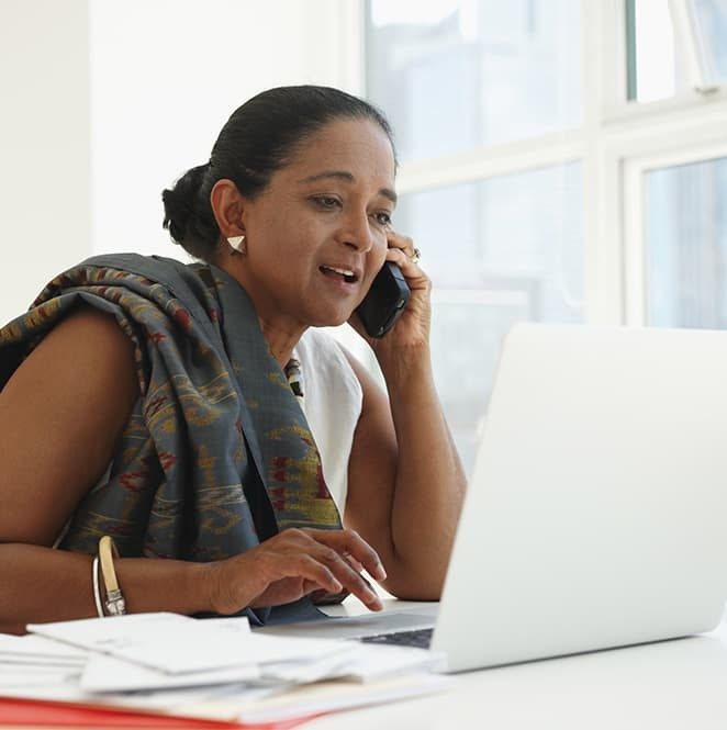 Woman on phone and laptop at work Woman on phone and laptop at work