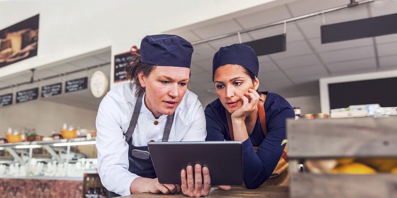 Chefs looking at tablet together in kitchen