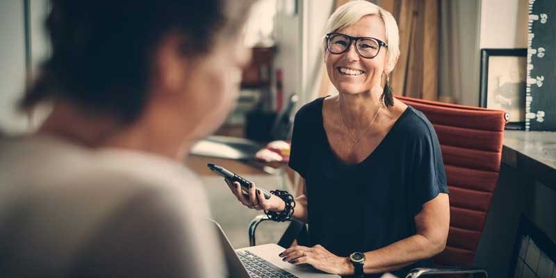 Employer on her phone while happily chatting with client