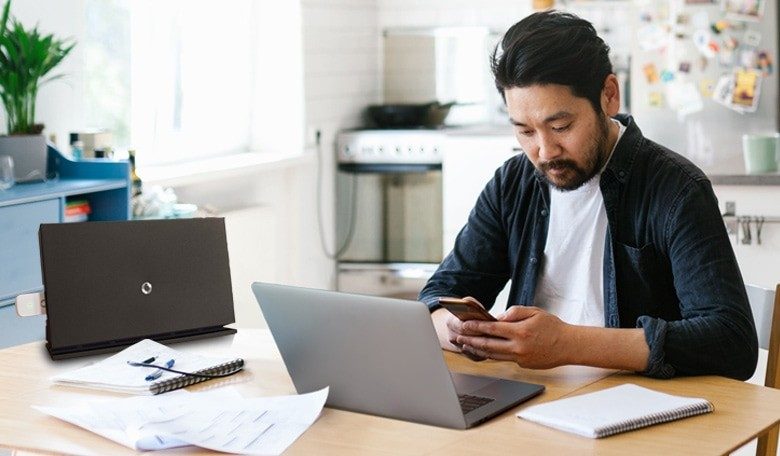 Man typing on phone as he takes break from laptop work