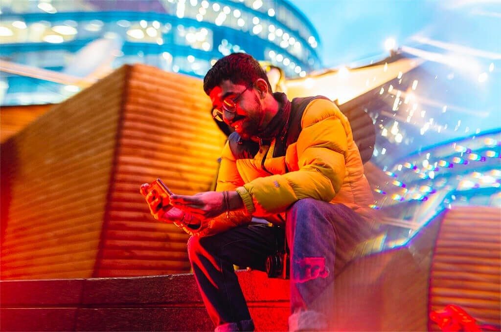 Guy sitting and looking at his phone screen.