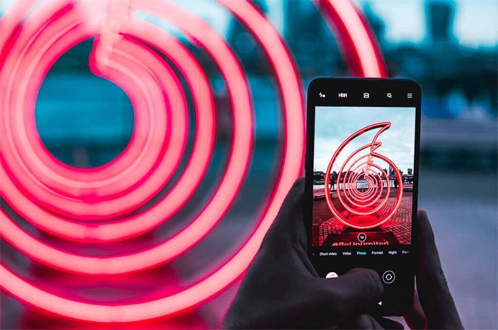 Phone screen taking a photo of a Vodafone roundel light sculpture.